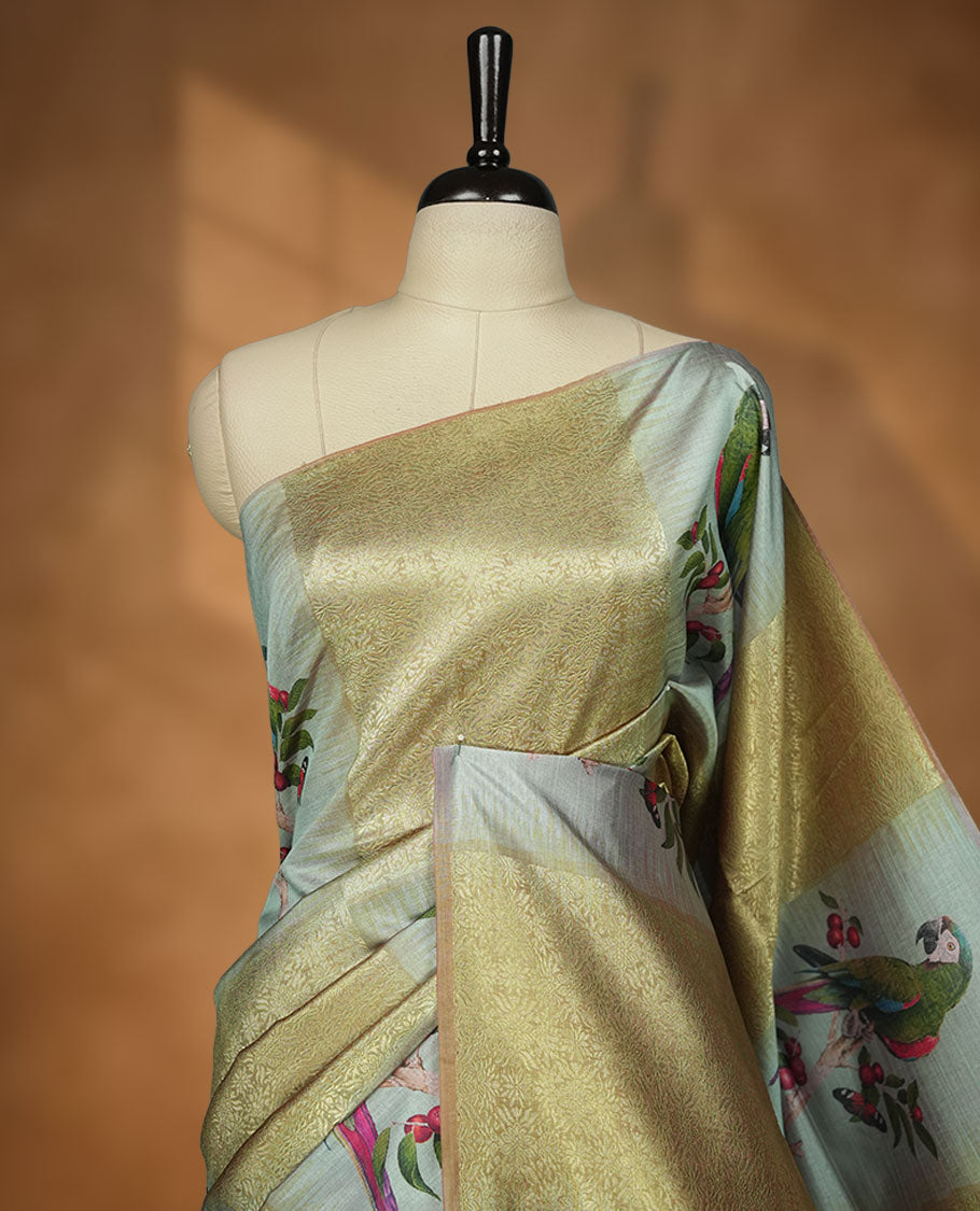 Parrot Green colour semi tussar Banarasi saree featuring vibrant multi-color floral prints across the body, with geometric zari patterns, and a matching blouse detailed with silver woven buttas.
