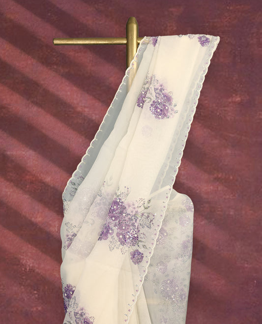 White colour pure organza saree featuring purple Colour floral prints with intricate bead and sequin work across the body, adorned with a matching embellished border, complemented by a worked pallu and paired with a heavily worked matching blouse.