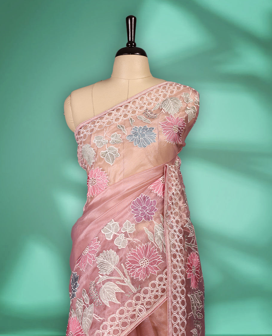 Lignt Pink colour organza designer saree featuring delicate pastel floral embroidery in pink, mint green, and white across the body, with a scalloped border accentuated by floral threadwork, and a gracefully embroidered pallu paired with matching blouse.