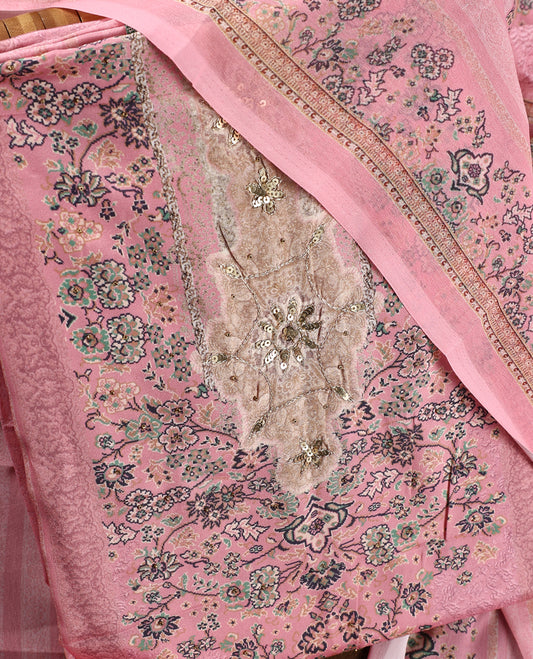 Pink colour churidhar material featuring delicate floral prints and intricate embroidery on the neckline, paired with a matching printed dupatta and a plain bottom.