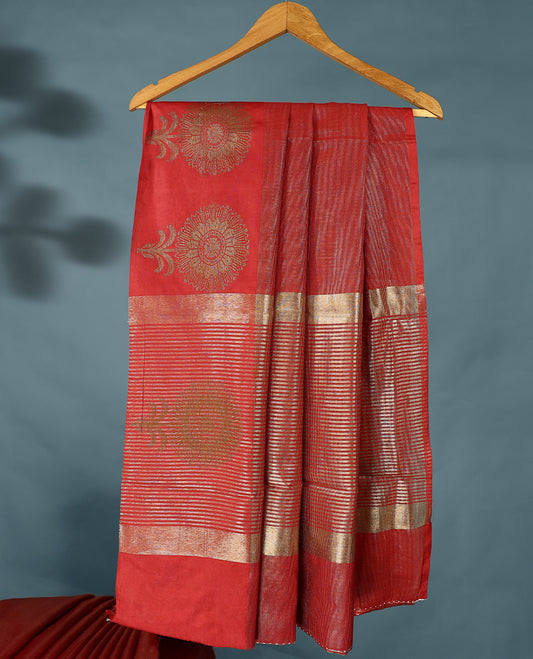 Red Colour Semi Tussar Silk saree featuring golden zari horizontal lines across the body, adorned with bold Floral motifs on the border, paired with a matching blouse.