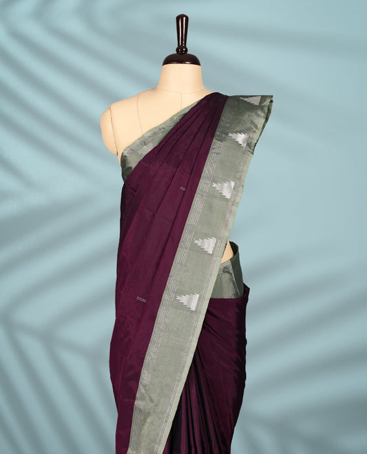 Burgundy Colour semi silk saree features an all over silver zari pattern and a sage green border adorned with traditional temple motifs, paired with a matching blouse.