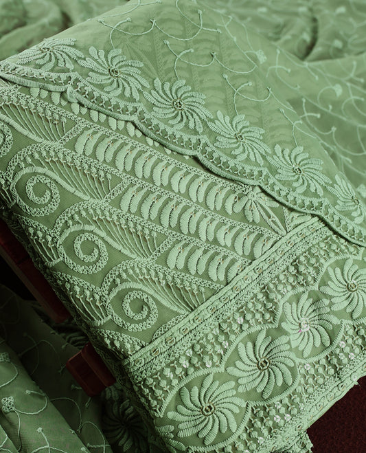 Elegant pastel green churidhar material adorned with intricate floral embroidery and delicate sequin highlights, paired with a plain matching bottom and embroidered dupatta, perfect for festive celebrations and graceful occasions.