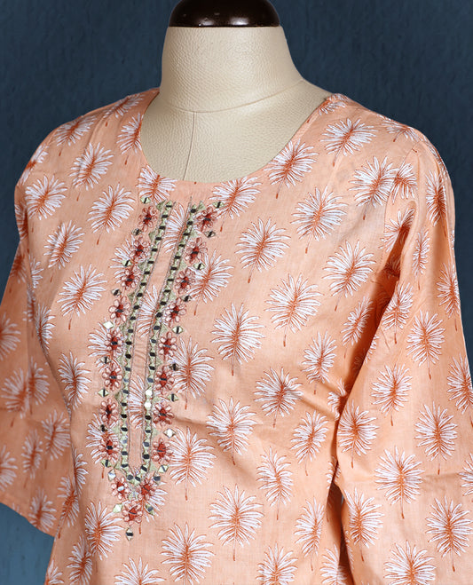 Peach colour kurti with all over white floral prints, featuring a round neckline adorned with vertical thread and mirror embroidery, and three quarter sleeves