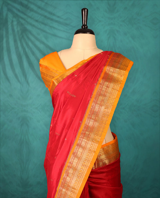 Deep Red colour Traditional Kancheepuram Silk saree with small gold motifs on body, orange colour traditional border with intricate gold zari weaving, grand zari pallu, perfect for Bharatanatyam, with matching blouse.