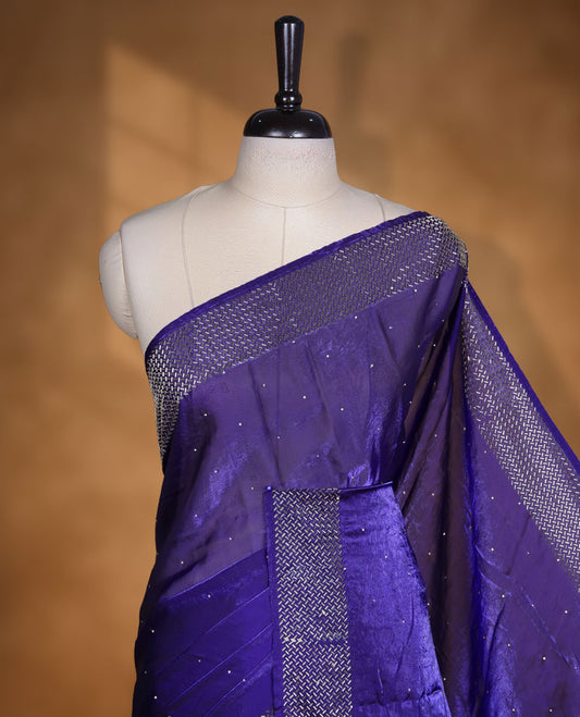 Dark violet colour chiffon designer saree, featuring dainty scattered stones on the body, enriched with dense stone work and a heavy metallic stone border and pallu, paired with a matching blouse.