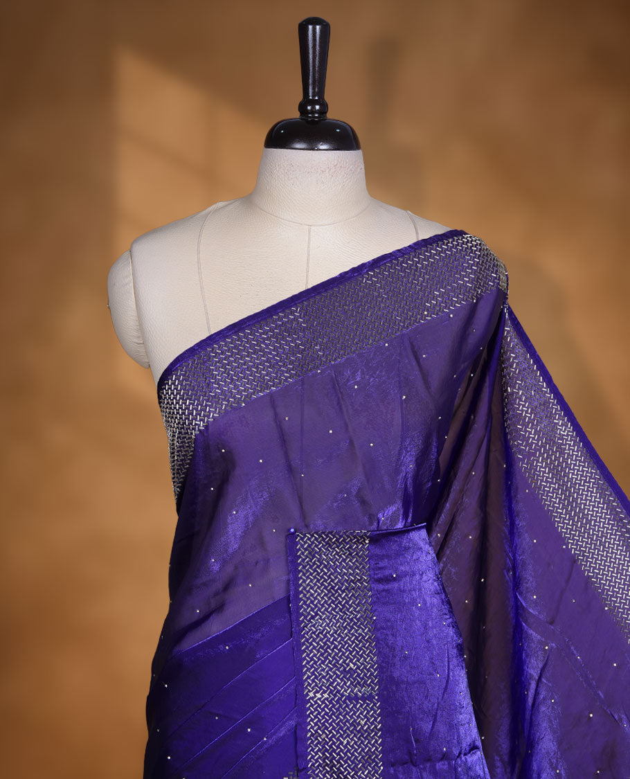 Dark violet colour chiffon designer saree, featuring dainty scattered stones on the body, enriched with dense stone work and a heavy metallic stone border and pallu, paired with a matching blouse.