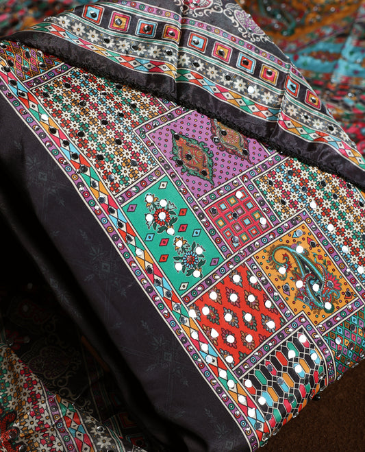 Striking black churidhar material featuring vibrant multicolour geometric and paisley prints highlighted with delicate mirror work, paired with a plain matching bottom and bold printed dupatta, ideal for festive occasions.