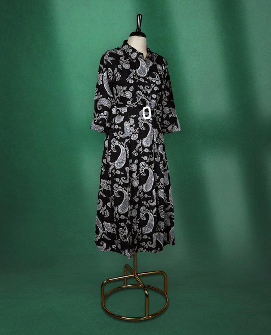 Black shirt style kurti dress featuring elegant white paisley prints, designed with a collared neckline, front buttons, 3/4th sleeves, and a matching fabric belt to accentuate the waist perfect for a smart Indo western look.