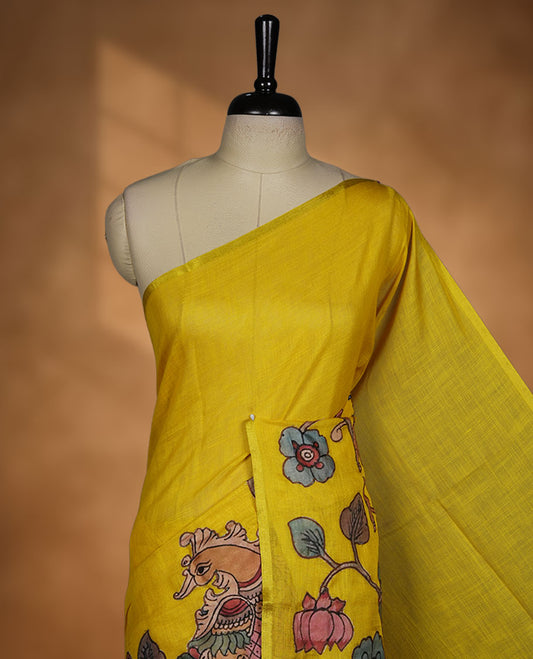 Mustard yellow semi linen saree featuring hand painted floral and bird motifs along the pallu and lower body, finished with a subtle border and paired with a matching printed blouse.