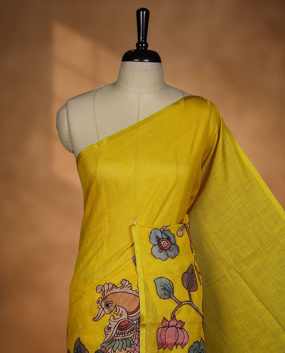 Mustard yellow semi linen saree featuring hand painted floral and bird motifs along the pallu and lower body, finished with a subtle border and paired with a matching printed blouse.
