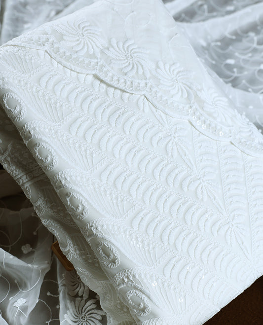 Elegant white colour churidhar material embellished with intricate floral embroidery and detailed thread patterns, paired with a plain matching bottom and embroidered dupatta, ideal for festive and elegant occasions.