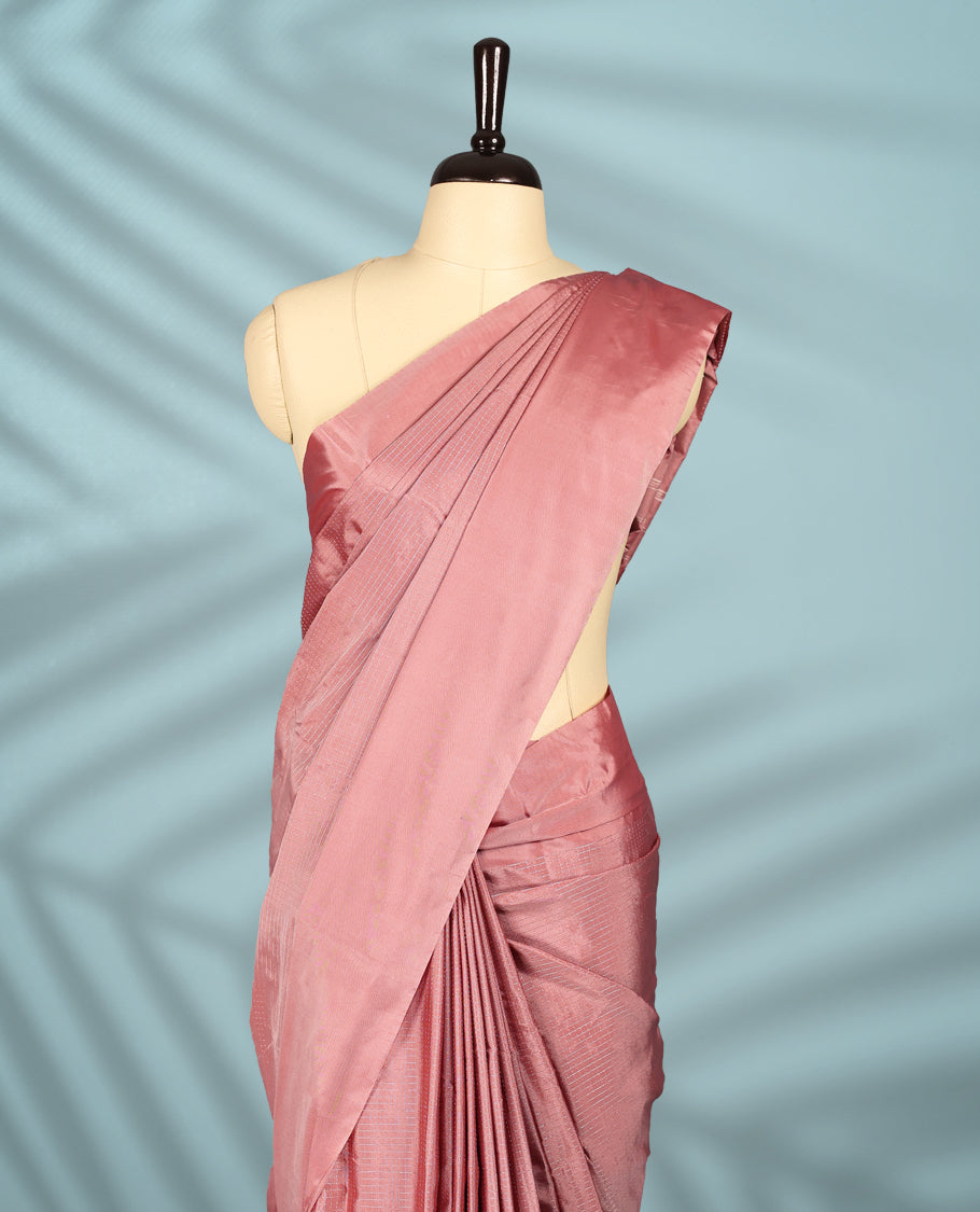 Peach pink colour semi silk saree featuring subtle textured checks on the body, complemented by a self-tone border, and comes with a matching blouse.