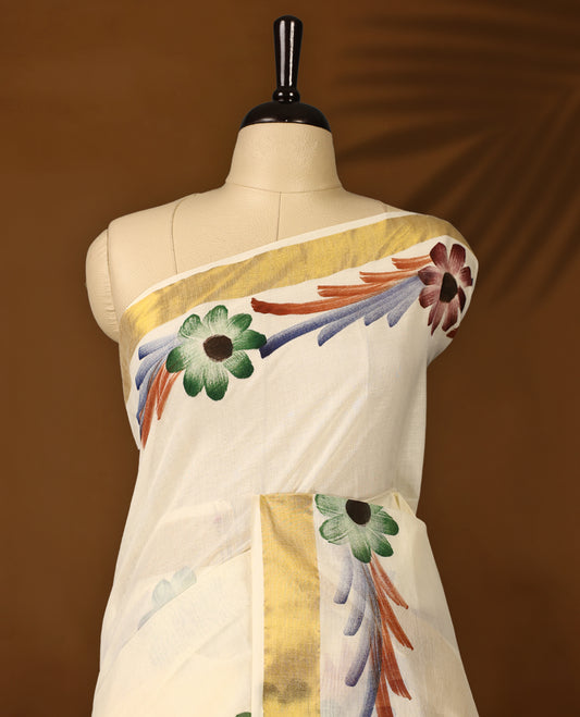Elegant Off White Colour Kerala Cotton Saree adorned with hand painted floral motifs in earthy tones,Highlighted with a classic Gold Kasavu border and matching blouse, perfect for festive and traditional occasions.