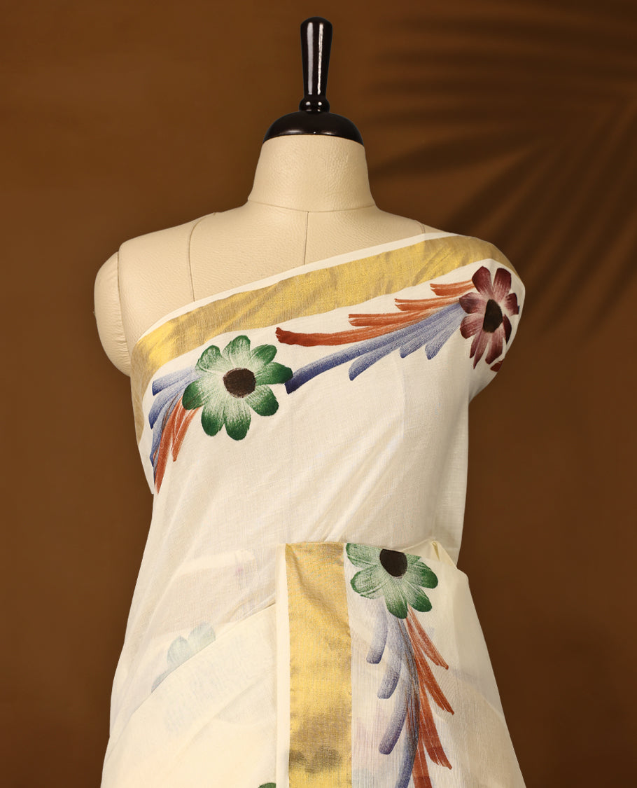 Elegant Off White Colour Kerala Cotton Saree adorned with hand painted floral motifs in earthy tones,Highlighted with a classic Gold Kasavu border and matching blouse, perfect for festive and traditional occasions.