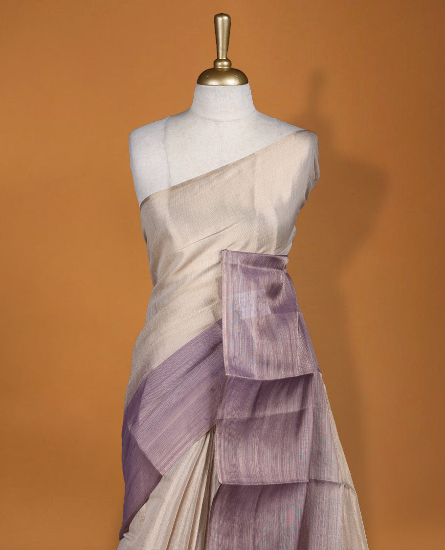 Beige and Lavender colour saree featuring a subtle woven texture & The shaded lavender pallu adds a graceful charm & Finished with delicate tassels and paired with a matching blouse piece.
