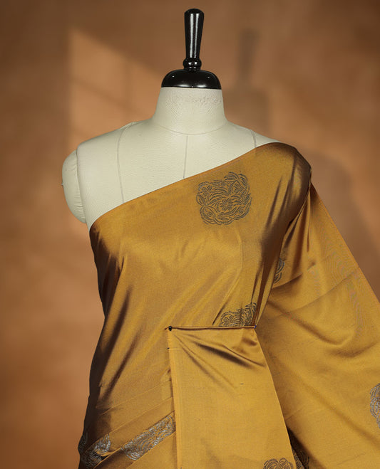 Dark mustard colour semi soft silk saree adorned with delicate woven motifs on the body, complemented by a Contrast rouge colour woven pallu with intricate detailing and tassel accents without border & Comes with a matching blouse piece.