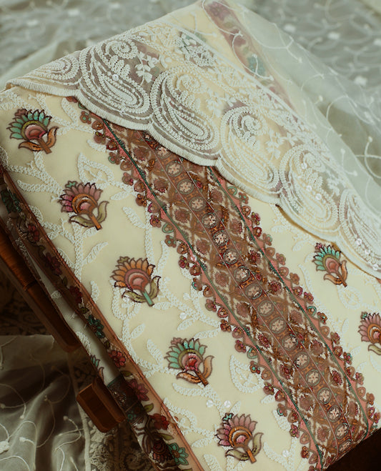 Cream and Peach churidhar material with floral thread & sequin embroidery, paired with a soft plain bottom & Comes with a sheer embroidered dupatta with fine lace borders & floral motifs for an elegant, graceful look.