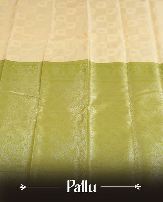 Light cream colour semi silk saree adorned with silver zari designs on the body, complemented by a contrasting olive green border and pallu, and paired with a matching blouse piece.