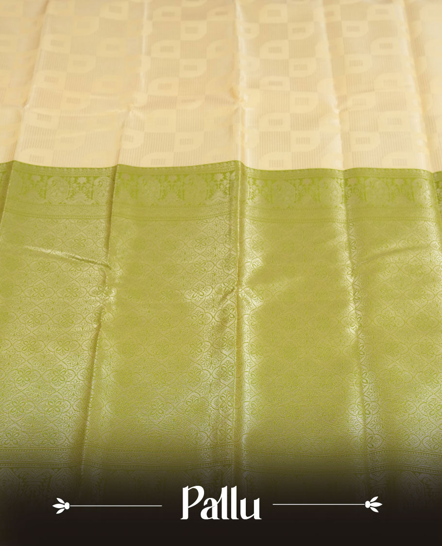 Light cream colour semi silk saree adorned with silver zari designs on the body, complemented by a contrasting olive green border and pallu, and paired with a matching blouse piece.