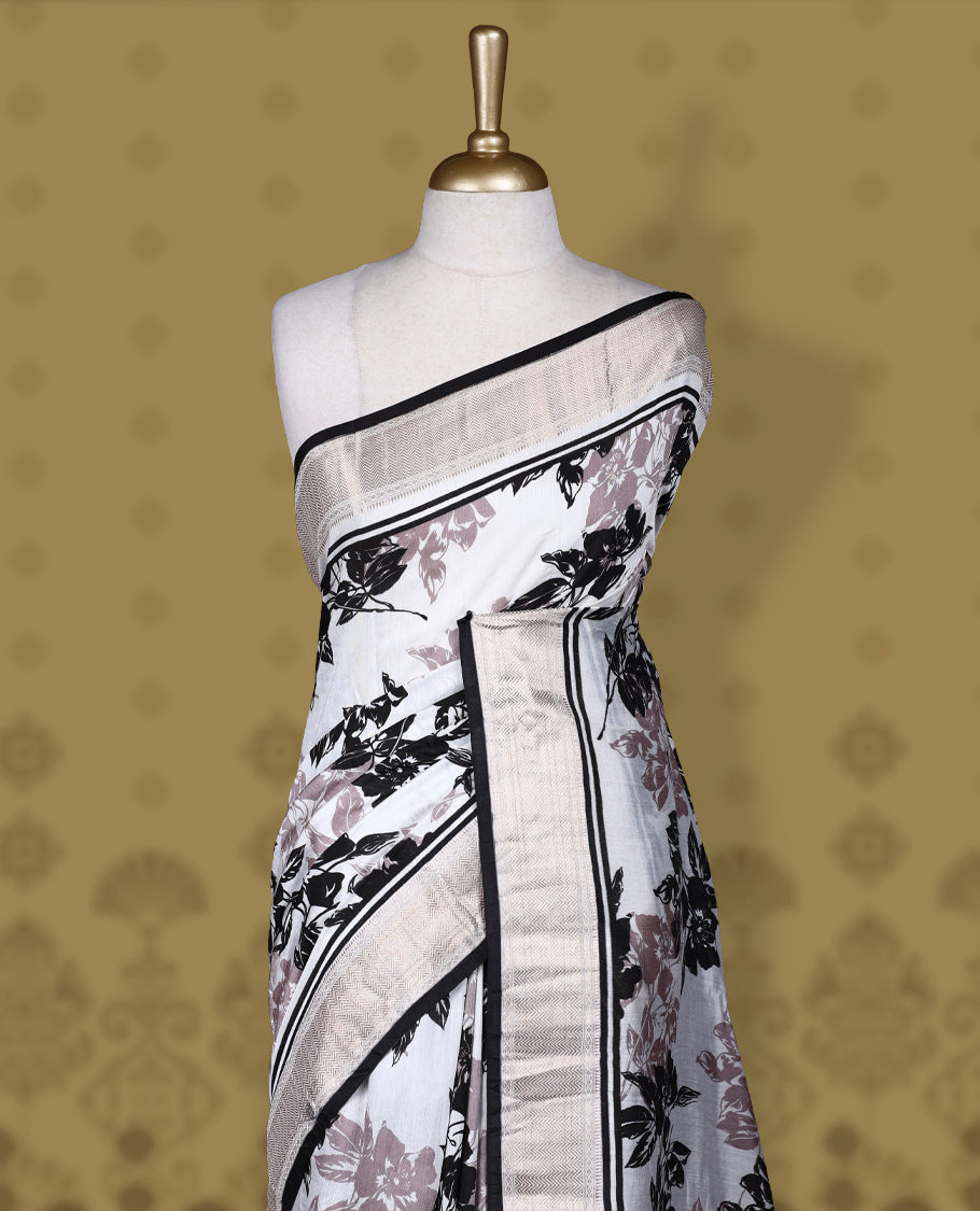 White colour saree with black and mauve floral prints, featuring a contrast zari border and detailed pallu & Comes with a matching blouse piece.