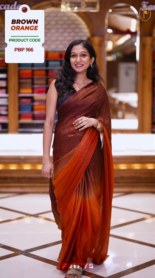 Brown orange colour saree with a soft textured body in deep orange, a rich pallu blending brown hues, and a subtle, seamless border for a graceful and contemporary drape & Comes with a matching blouse.