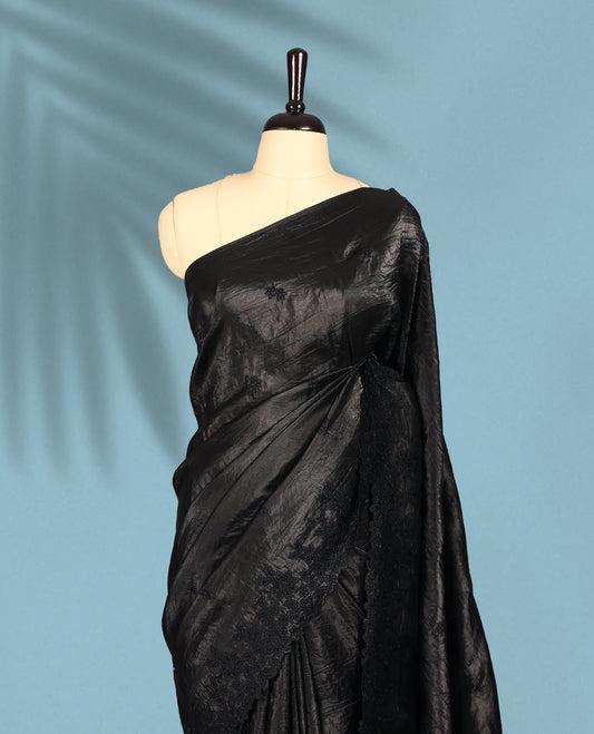 Black Colour crush soft silk saree boasts a lustrous crinkled texture with subtle self colored floral Motifs on the body and an elegant Floral thread cutwork border, paired with a matching blouse.