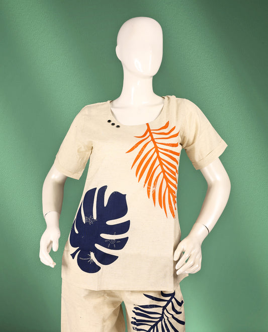 Beige colour cotton nightwear featuring bold navy blue and orange tropical leaf prints, a round neck top with short sleeves, and relaxed-fit ankle-length pants for a vibrant and breezy casual look.