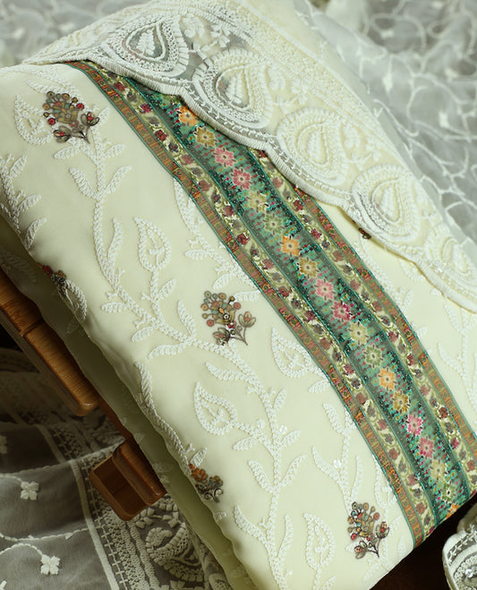 Cream colour churidhar material with embroidered green neck work, white thread floral motifs on the body, and multicolor detailing in green, pink & light brown &Comes with matching plain bottom and embroidered dupatta.