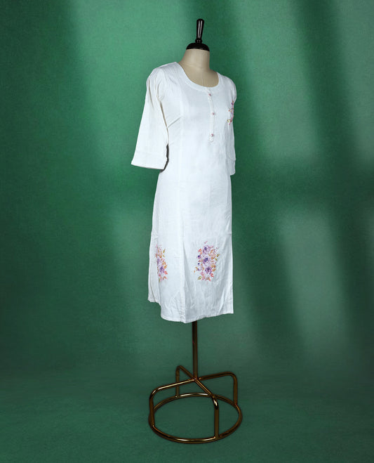 White colour cotton kurti featuring delicate floral prints in soft pastel shades with beads ans sequence work, scoop neckline with button detailing, and elbow length sleeves perfect for a graceful and breezy everyday look.