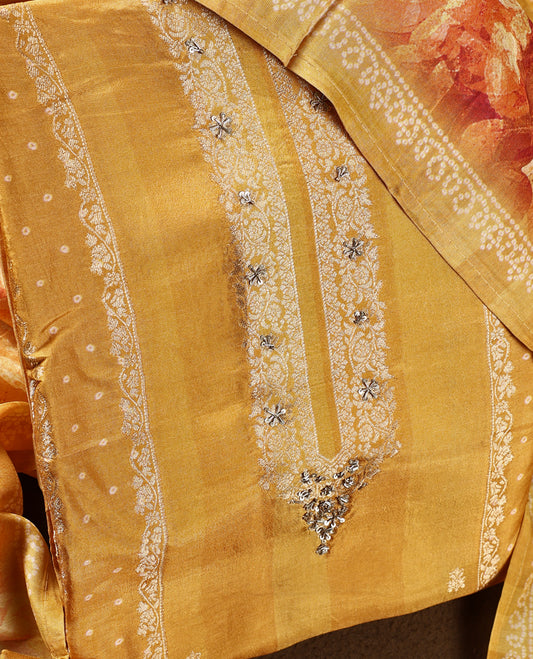 Mustard yellow colour churidhar material featuring delicate zari embroidery on the neckline, paired with a plain matching bottom and a floral printed dupatta with dotted patterns.