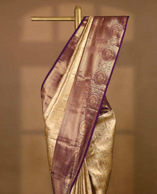 Gold colour tissue brocade saree with gold and silver zari floral pattern on body, gold zari traditional floral and chakkram work royal purple border, rich matching pallu with Antique zari motifs, paired with matching blouse.