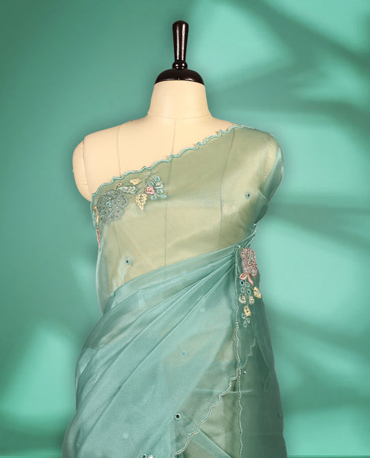 Light Blue Colour organza saree featuring delicate floral embroidery with applique, bead, mirror, and thread detailing on the body and scalloped border, lending a soft feminine charm, paired with a matching blouse.