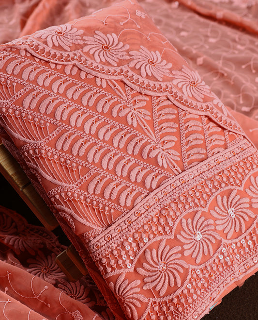 Charming peach pink colour churidhar material highlighted with intricate floral embroidery and delicate sequin accents, paired with a plain matching bottom and embroidered dupatta, perfect for festive gatherings and elegant occasions.