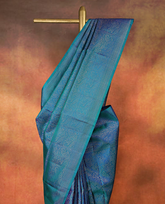 Teal green and royal blue dualtone pure Mayuri silk saree featuring intricate floral self weaving throughout the body, complemented by a finely detailed traditional border in matching tones, with matching blouse