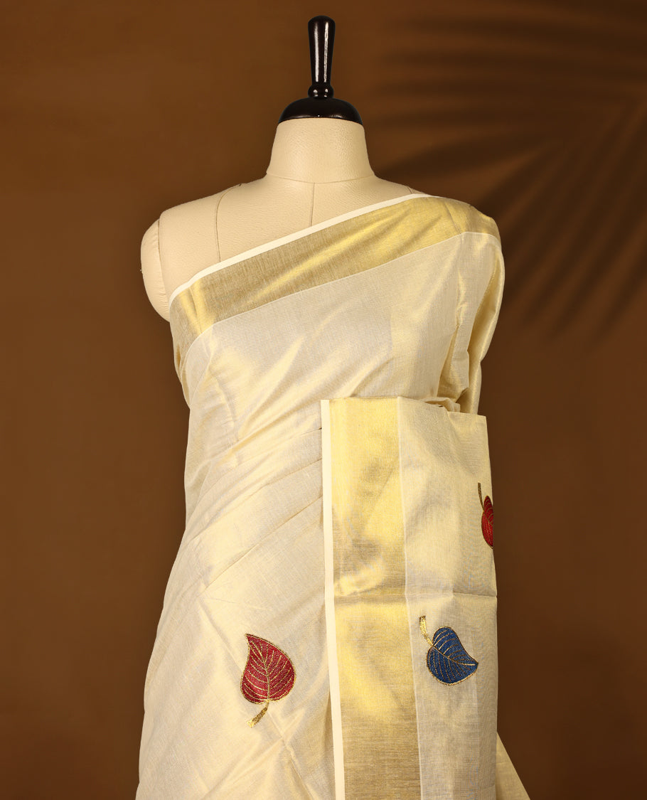 Light Gold colour Tissue Kerala saree featuring leaves Embroidery body and a beautifully woven Gold Kasavu border,  paired with a matching blouse perfect for festive occasions.