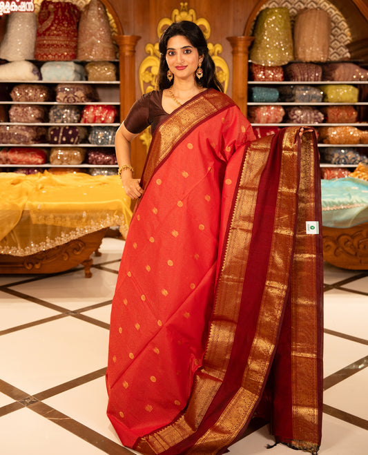 Red With Maroon Chettinad cotton saree featuring Gold zari strips with peacock motifs on body, complemented by contrast colour border with zari design & grand pallu, comes with matching blouse piece.