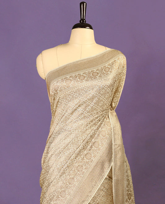 Off White colour semi Banaras Katan saree featuring an antique Gold zari jacquard body, complemented by a self colour traditional border with a floral kodi design, paired with a matching blouse
