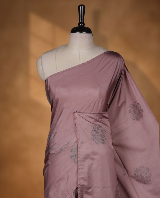 Pinkish beige colour semi soft silk saree adorned with delicate woven floral motifs on the body, complemented by a Self colour woven pallu with intricate detailing and tassel accents without border & Comes with a matching blouse piece.