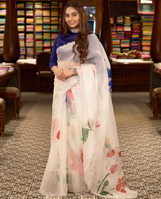 White colour pure organza silk saree featuring digitally printed fancy floral designs, adorned with delicate small mirror work, and finished with an elegant scalloped border, paired with a self colour crepe printed blouse