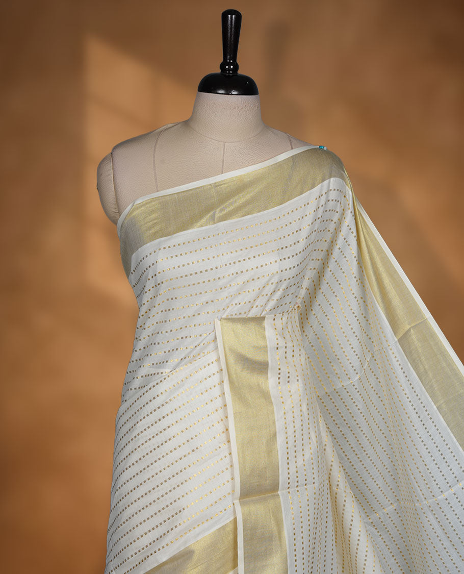 Off white colour cotton Kerala saree featuring fine dotted zari lines on the body, complemented by a classic golden zari border and traditional pallu, paired with a matching blouse.