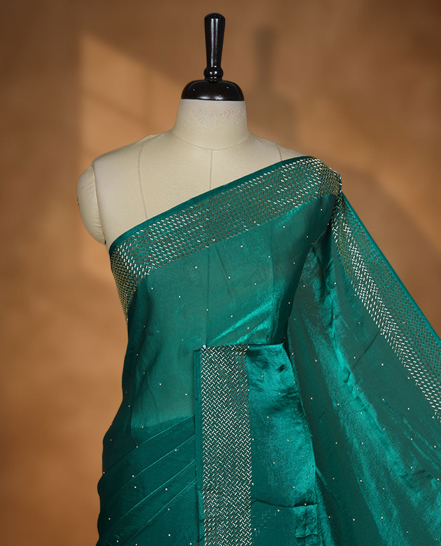 Emerald green chiffon designer saree, featuring dainty scattered stones on the body, enriched with dense stone work and a heavy metallic stone border and pallu, paired with a matching blouse.