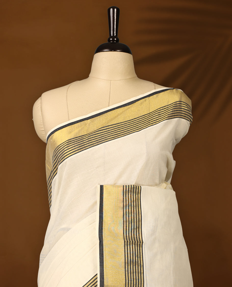 Classic pure cotton Kerala saree with a cream base, golden zari border, and elegant black striped detailing, A timeless choice for traditional events and festive occasions & Comes with a matching blouse piece.