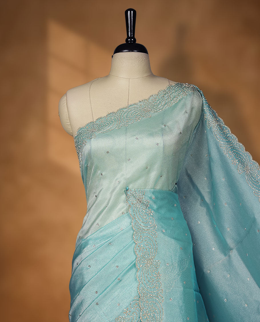 Pastel aqua blue  Colour net shimmer fancy saree adorned with scattered white stone buttas all over the body, paired with a delicate stone worked border and matching blouse featuring floral vine stone embroidery.