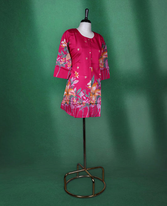 Fuchsia pink colour short kurti featuring a round neck and three quarter sleeves, adorned with vivid orange floral prints and minimal front buttons for a vibrant, breezy look.