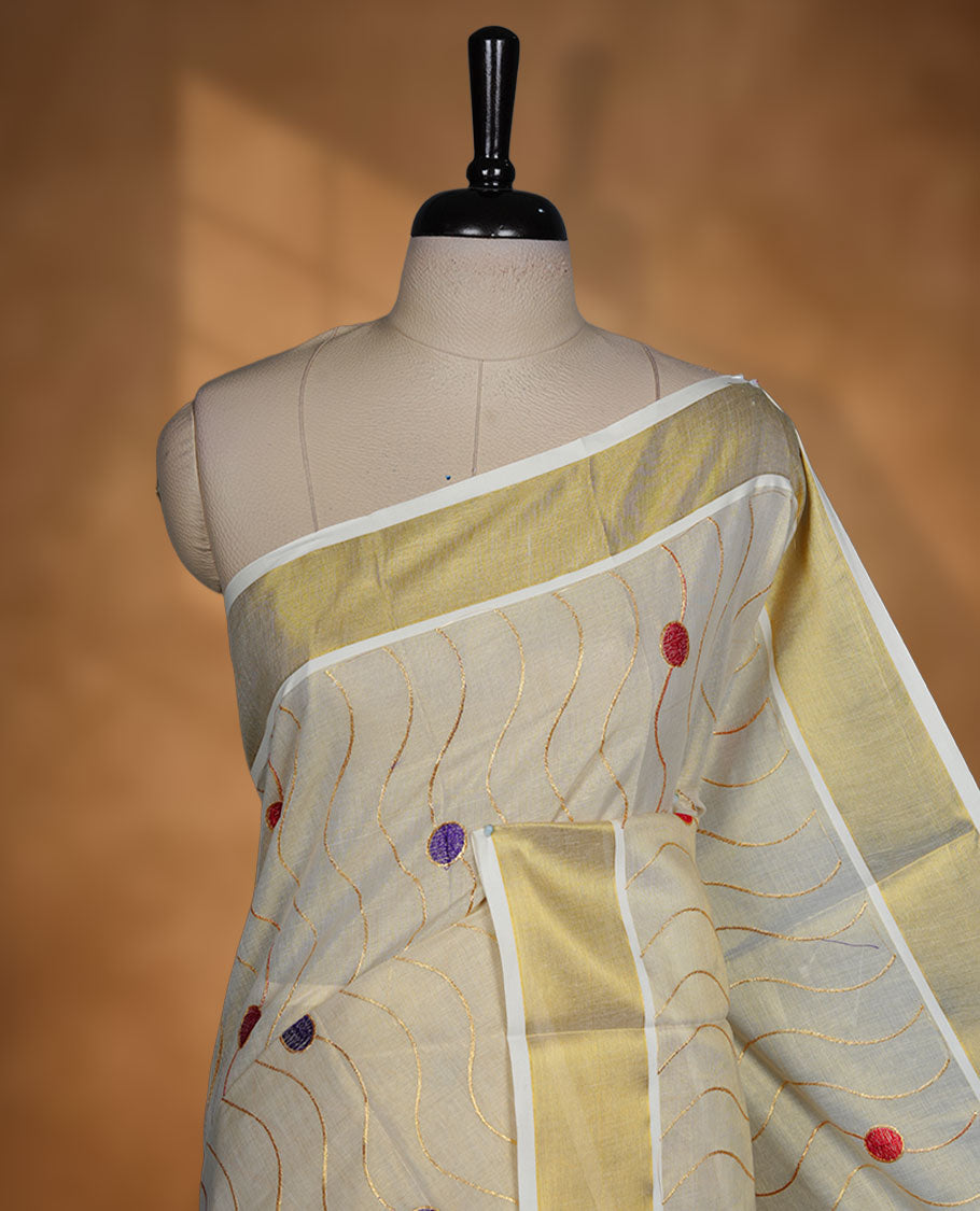 Off white colour cotton Kerala saree with wavy zari lines and colourful red and purple motifs, complemented by a classic golden zari border and matching blouse.