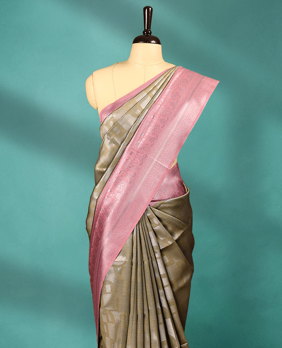 Dark Olive coloured semi silk saree featuring a Silver coloured Zari design on the body, paired with a Onion coloured border and blouse.