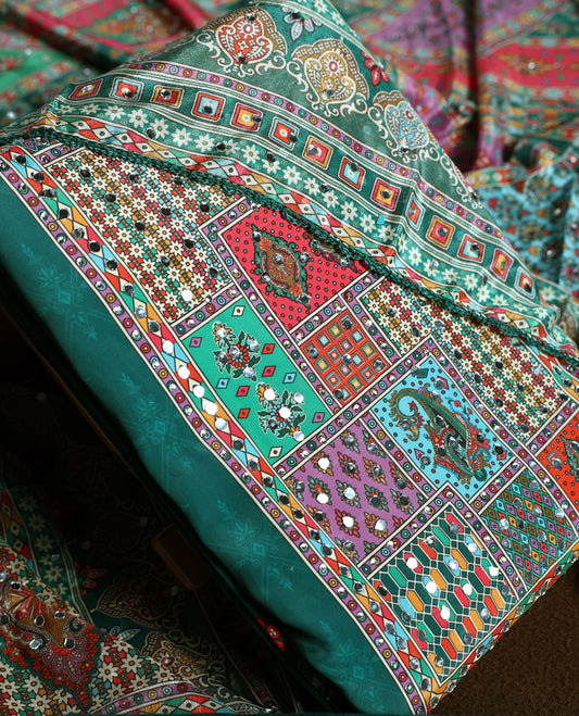 Green colour churidhar material with vibrant multicolour geometric and paisley prints, enhanced with delicate mirror work, paired with a plain matching bottom and bold printed dupatta, perfect for festive occasions.