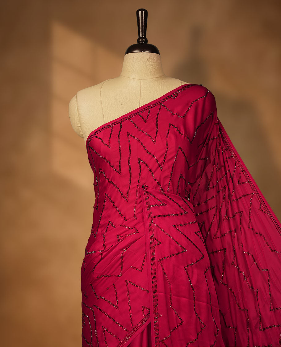 Dark Red Colour net shimmer fancy saree adorned with red stone buttas all over the body, paired with a delicate stone worked border and matching blouse featuring floral vine stone embroidery.