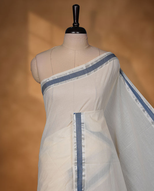Off-white colour cotton Kerala saree highlighted with teal blue kasavu border, featuring a clean, minimalist body and a graceful flowing pallu, paired with a matching blouse.